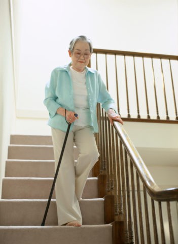 杖をついて階段を降りる老婦人