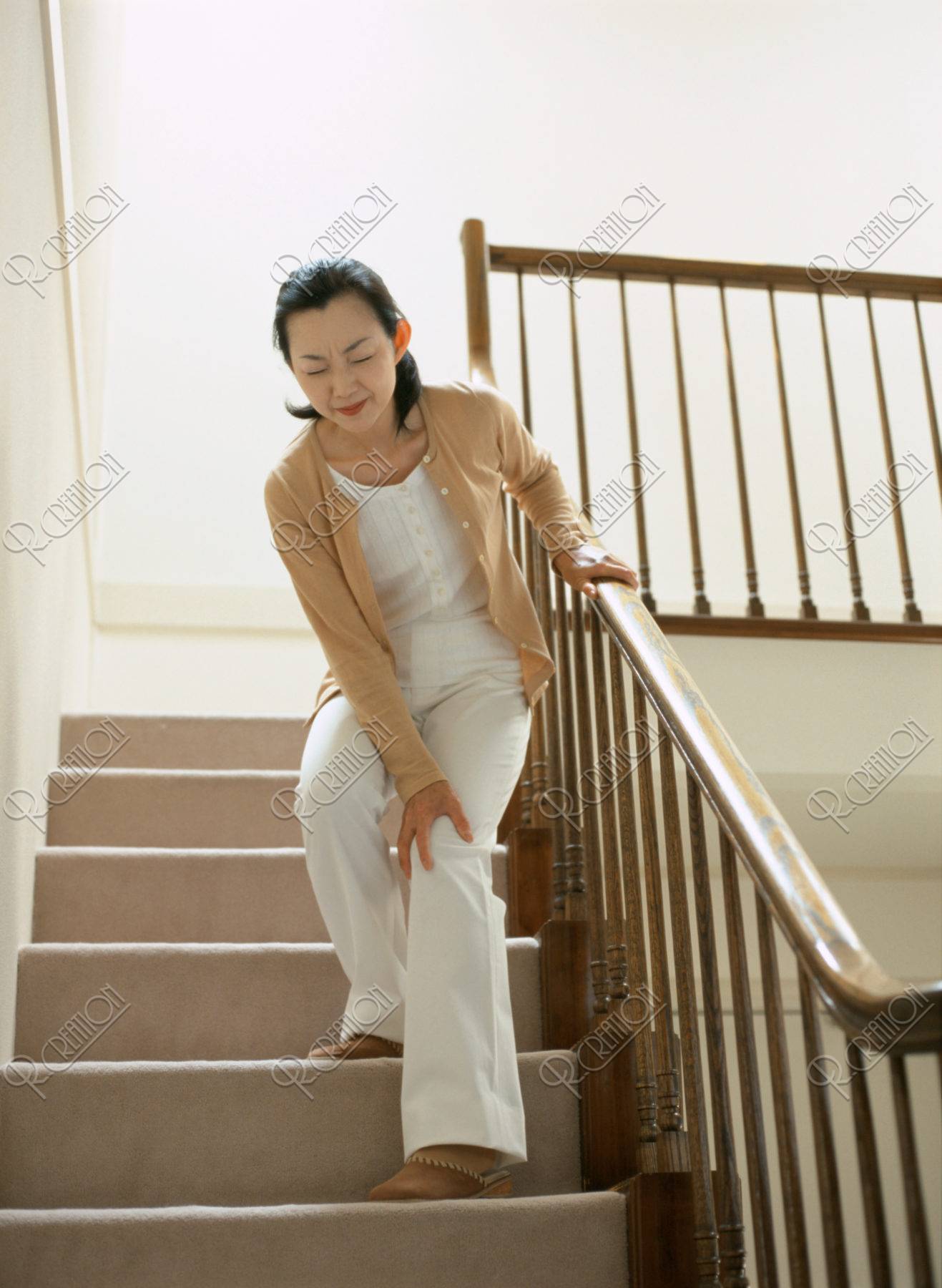 痛みをこらえて階段を降りる女性 ストックフォト アールクリエーション
