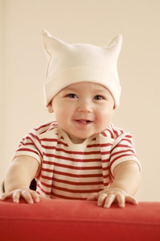 赤ちゃん 白い帽子 赤いソファ