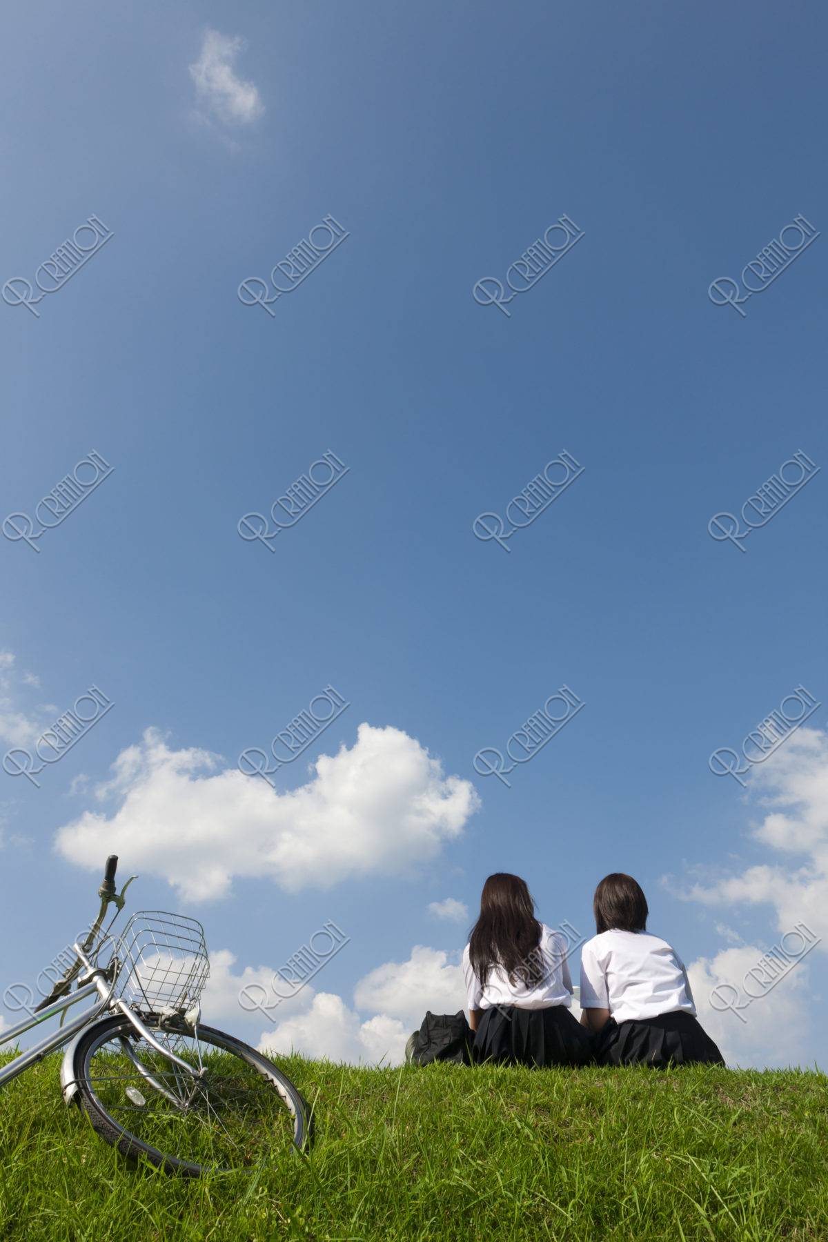 土手に座っておしゃべりする二人の女子高校生 ストックフォト アールクリエーション